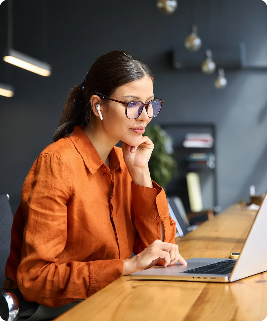 Woman in orange shirt using a laptop.