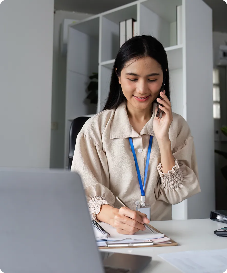 Woman multitasking on phone and writing notes.